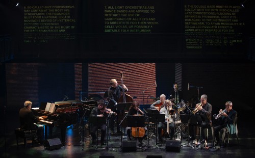 "Dance to the Abyss" (L-R): Andrew Burashko, Drew Jurecka, Andrew Downing, Lydia Munchinsky, Nathan Hiltz, Kelsley Grant, Kris Maddigan, Kevin Turcotte, Larry Larson. Text as displayed is from Czech/Canadian fiction writer Joseph Škvorecký’s story “Eine Kleine Jazzmusik”, published in 1966. Photo by John Lauener